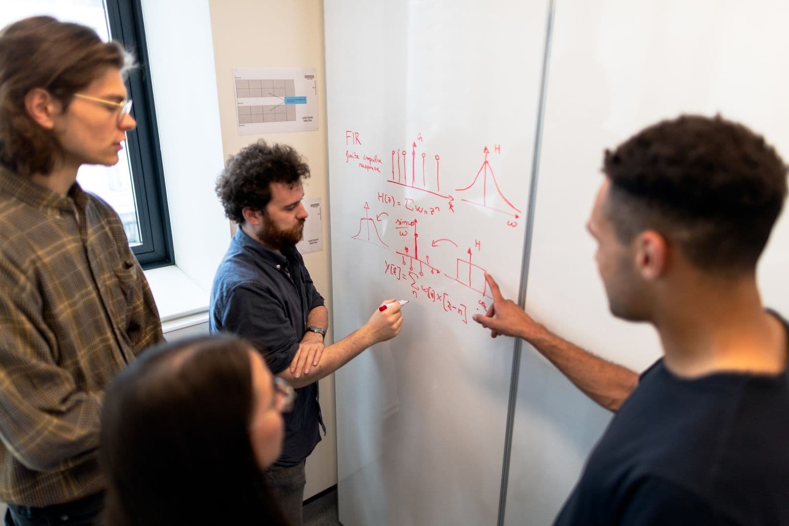 Des professionnels examinent des schémas sur un tableau blanc.